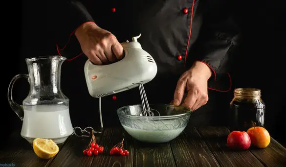 chef making milk fruit shake with electric hand mixer or appliance