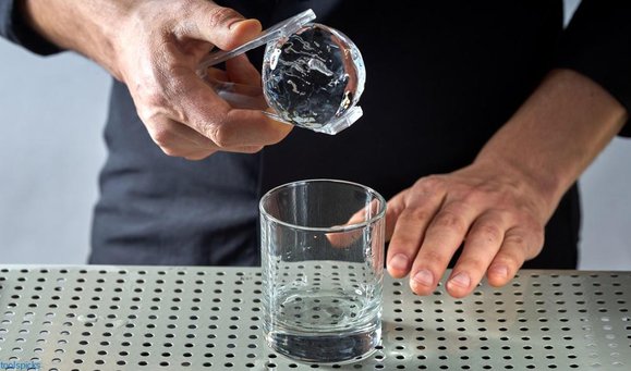 professional bartender is holding an ice ball close up